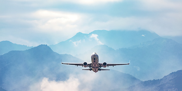 Airplane flying with mountains in the background