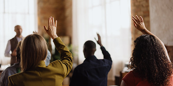 People in a room with their hands up to ask a question