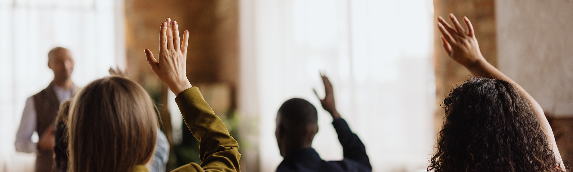 People in a room with their hands up to ask a question